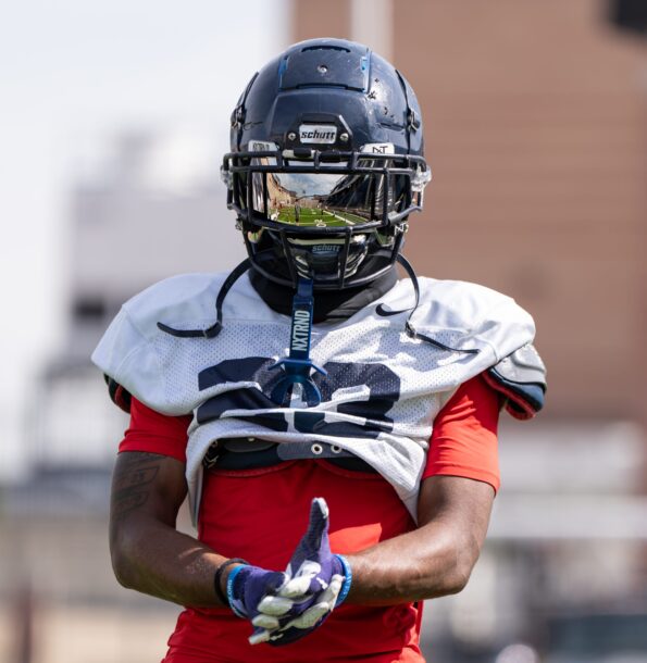 A focused football player wearing a helmet and gloves, poised for the game, embodying strength and competitive spirit.